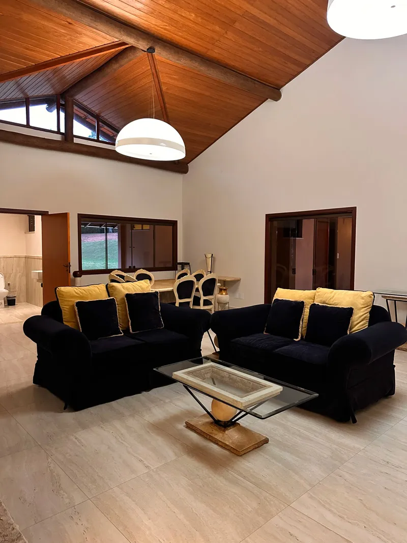 Sala principal compartilhada com sofás e teto de madeira