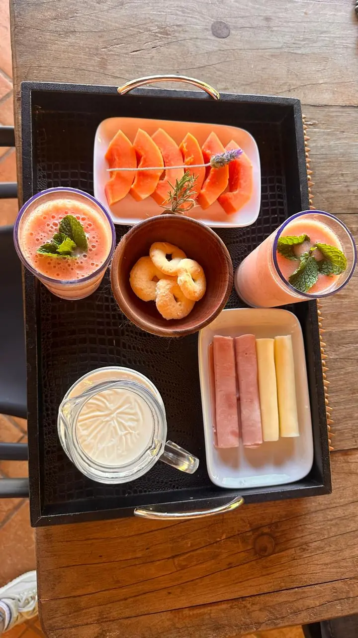 Bandeja com mamão, duas bebidas com hortelã, biscoitos, presunto, queijo e uma jarra