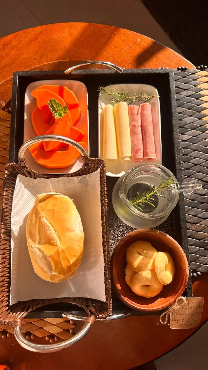 Bandeja com pão francês, mamão, frios, biscoitos e uma jarra