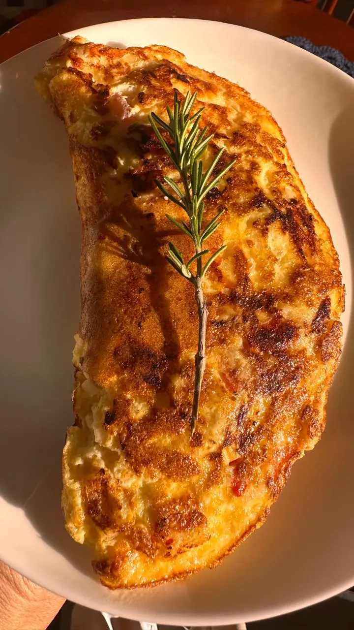Omelete dobrada em um prato, com um ramo de alecrim